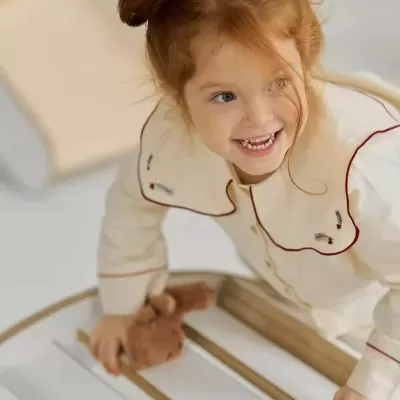 Menina ruiva com pijama creme e brinquedo de pelúcia castanho