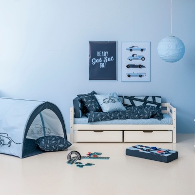 Quarto infantil azul com peças de mobiliário branco, tenda, cama com padrão de carros e decoração temática