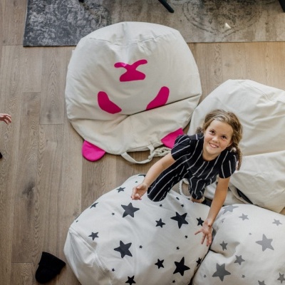 duas crianças numa sala com pufs grandes de tecido branco com padrões pretos e rosas