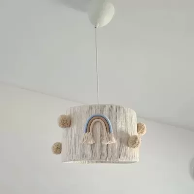 Luminária de tecto bege com textura de corda, pompons e arco-íris azul e bege.