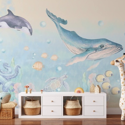 Parede infantil marinha com golfinhos, baleia, polvo e tartaruga junto a móvel branco e girafa de peluche