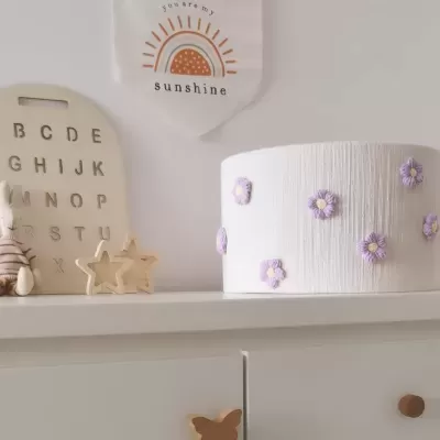 Prateleira com caixa decorada, placa com alfabeto, estrelas decorativas, coelho de peluche e placa com texto e desenho de sol