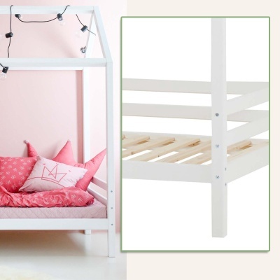 Cama infantil branca em forma de casa com almofadas rosas e luzes LED