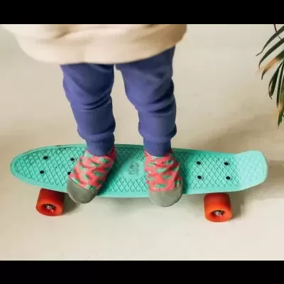 Criança em cima de skate verde claro com rodas laranja