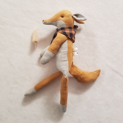 Peluche raposa castanha com cachecol xadrez sobre superfície branca