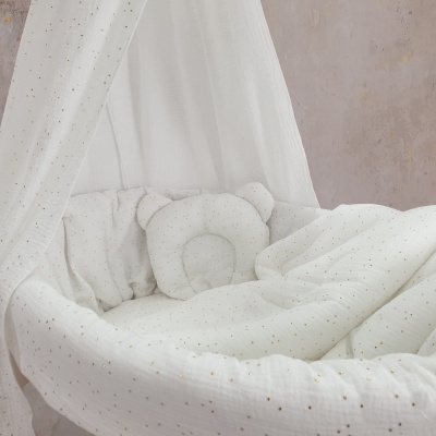 Berço de bebé branco com almofada em forma de urso e tecido com pontos dourados