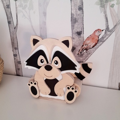 Figura decorativa de guaxinim em madeira com fundo de papel de parede de árvores e pássaro.