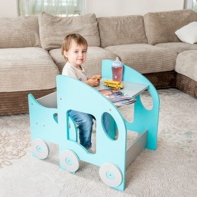 Mesa e cadeira infantis azuis em forma de veículo com rodas brancas numa sala com sofá castanho