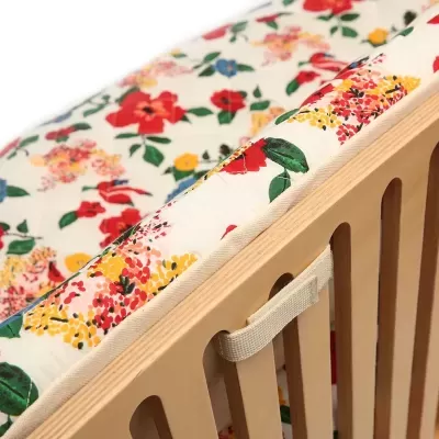 Cama infantil com colchão estampado floral e estrutura de madeira clara