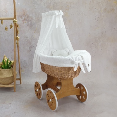 Berço móvel de verga com cobertura branca e rodas de madeira