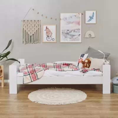 Cama infantil branca com cobertor xadrez e decoração de parede cinza com tapeçaria e quadros