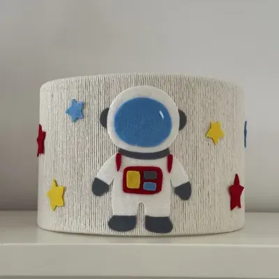 Abajur bege com decoração de astronauta e estrelas em feltro colorido