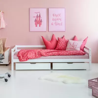 Cama infantil branca com almofadas e edredão rosa e duas molduras decorativas rosa na parede