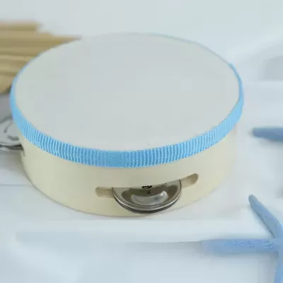 Pandeireta com pele branca e fita azul clara sobre tecido branco com estrela-do-mar azul