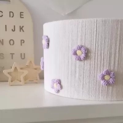 Abajur branco texturizado com flores lilases bordadas e decoração de madeira em fundo branco
