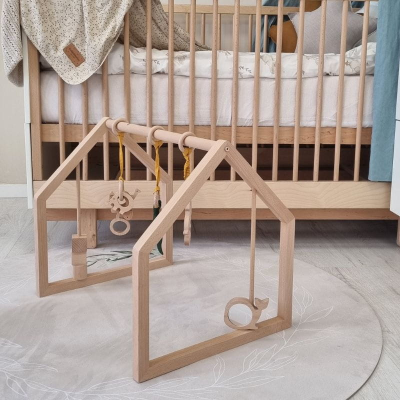 Brinquedo de madeira para bebé em forma de triângulo junto a berço de madeira clara