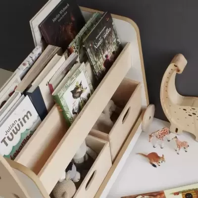 Estante infantil de madeira clara com livros e brinquedos organizados, caixa de armazenamento com rodinhas.