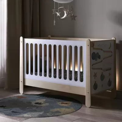 Berço de madeira clara com frisos brancos e painel lateral decorativo em quarto infantil