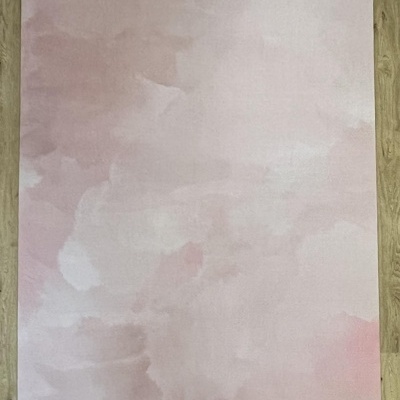 Tapete retangular rosa claro com padrão em tons suaves sobre chão de madeira clara