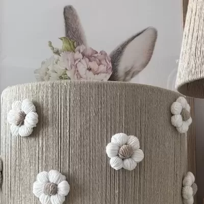 Armazenamento redondo cinzento com flores decorativas e quadro com orelhas de coelho atrás