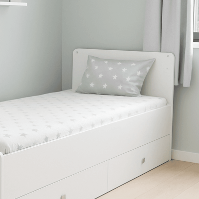 Cama individual branca com colchão e almofada com padrão de estrelas cinzentas num quarto claro