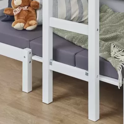 Cama branca com colchão cinzento e urso de pelúcia em cima