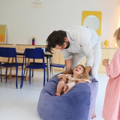 Pufe azul claro em veludo com crianças a brincar em ambiente interior moderno