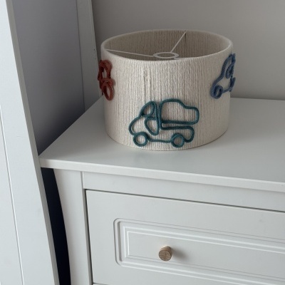 Abajur branco com carrinhos coloridos numa cómoda branca