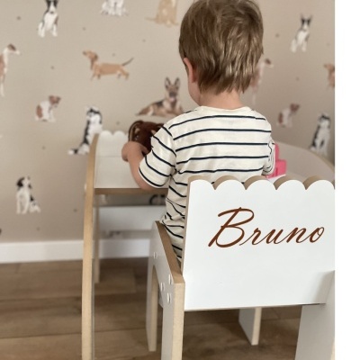 Cadeira e secretária branca de madeira para criança com nome Bruno, menino de costas sentado, papel de parede com cães