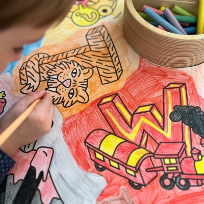 Criança a colorir desenho infantil com lápis de cor e caixa redonda de madeira