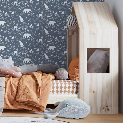 Quarto infantil com cama, roupa de cama laranja, parede azul com padrão de animais e casa de madeira clara