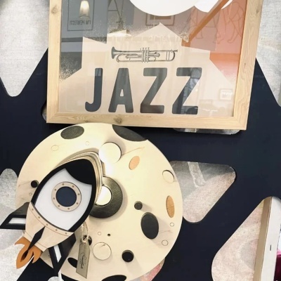 Moldura com a palavra JAZZ e objeto decorativo redondo com desenho da lua e foguete