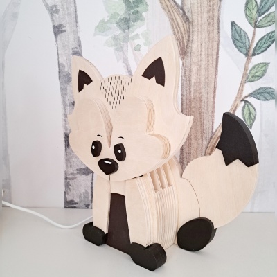 Abajur de raposa em madeira com pintura preta, em ambiente com fundo decorado com árvores.