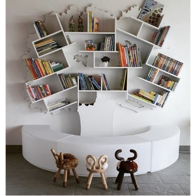 Estante de parede branca em forma de árvore com livros e três bancos infantis em madeira