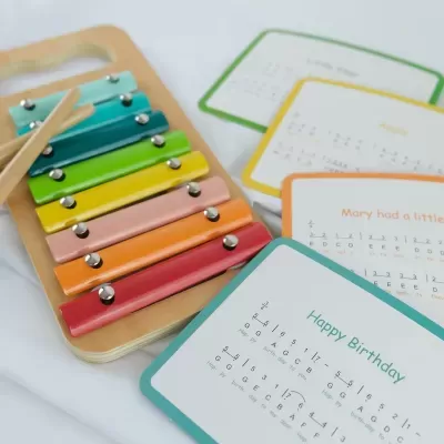 Xilofone colorido de madeira com teclas metálicas e cartas com partituras musicais
