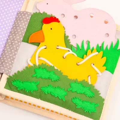 Página de livro interativo de tecido com pintainho amarelo de feltro e coelho cor-de-rosa