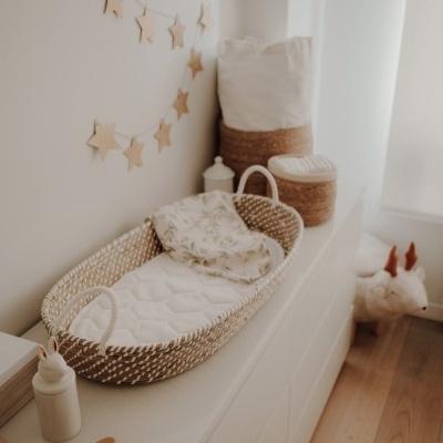Cama de bebé moisés trançada com colchão branco, tecido às folhas e decoração de estrelas na parede