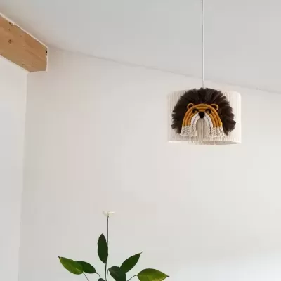 Luminária suspensa com abajur de crochê com rosto de leão em várias cores, pendurada em teto branco