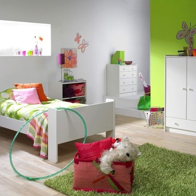Quarto infantil com cama, móveis brancos, roupa de cama verde com flores e autocolantes de borboletas na parede verde