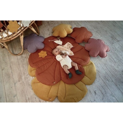 Tapete acolchoado com pétalas coloridas e bebé em cima