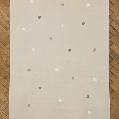 Tapete bege com pontos marrons e brancos sobre piso de madeira