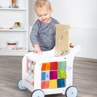 Carrinho de madeira branco com blocos coloridos numerados e labirinto de esferas, com bebé a brincar.