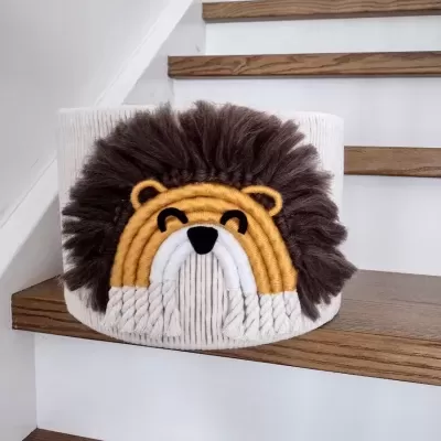 Cesta decorativa em forma de leão com juba castanha numa escada de madeira