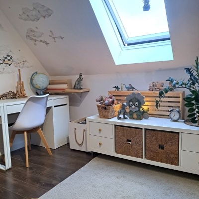 Quarto infantil com móveis brancos, decoração em madeira e janela de telhado com balão de ar quente