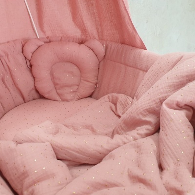 Têxteis de berço rosa claro com padrão de pontos dourados e almofada em forma de ursinho