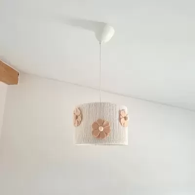 Lâmpada de teto branca com flores castanhas suspensa num teto branco com viga de madeira