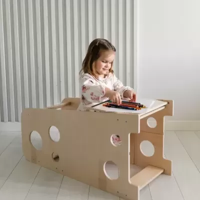 Menina a desenhar numa mesa infantil de madeira clara