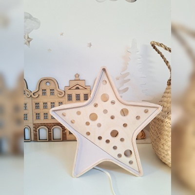 Luminária estrela em madeira com furos circulares e decoração de casas de madeira ao fundo