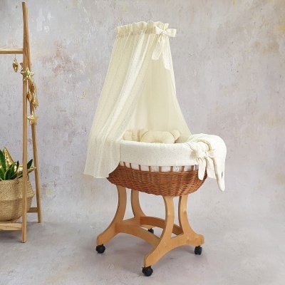 Berço de vime com tecido branco e redoma em ambiente com parede bege e escada de madeira