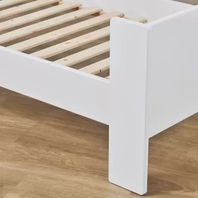 Estrado de cama em madeira branca e ripas naturais sobre chão de madeira clara.